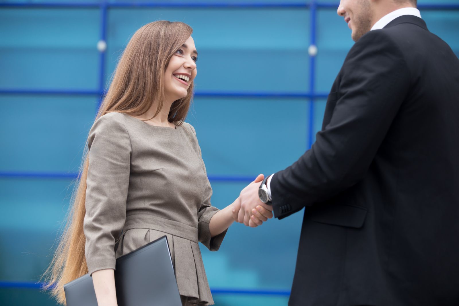 white-woman-in-dress-shaking-hands-white-businessman-traders-finance
