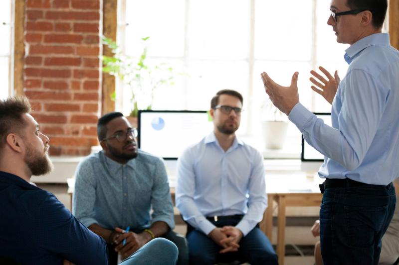 man-presenting-to-other-men-business-meeting-indoors-office-velox-clearing